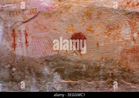 Ancient pictographs on rocky surface showcasing vibrant red and orange colors. Stock Photo