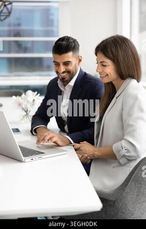 Coworkers collaborating on laptop in modern office Stock Photo