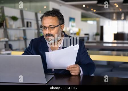 Businessman carefully reviewing performance reports in printed documents Stock Photo