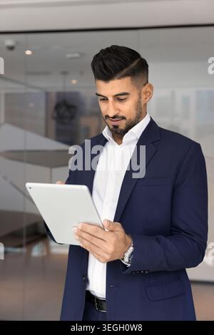 Handsome Indian businessman working on digital tablet in workspace Stock Photo