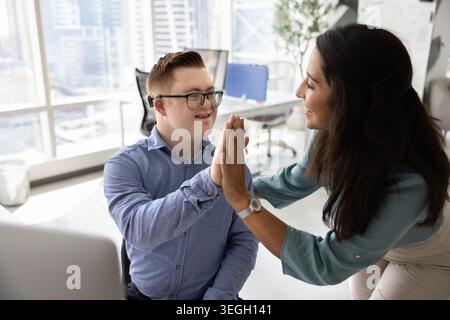 Woman giving high five to male colleague with Down syndrome Stock Photo