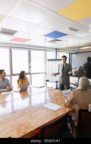 Adult businessman giving presentation to multiethnic team in corporate office Stock Photo