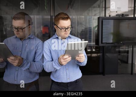 Young professional man with Down syndrome using tablet in office Stock Photo