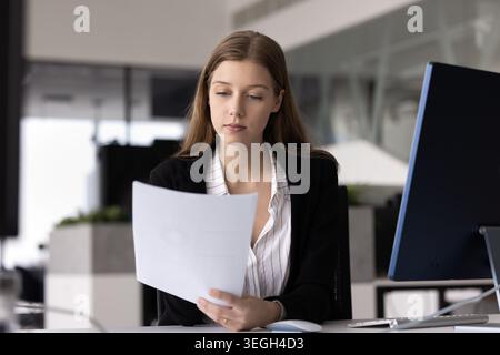 Businesswoman holds document and attentively reading it content Stock Photo