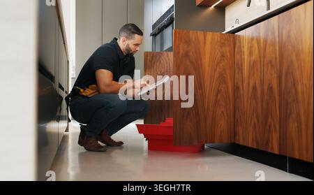 Inspection, plumber and man with tablet in kitchen for pipeline maintenance or valve corrosion. Digital tech, checklist or handyman with leak report Stock Photo