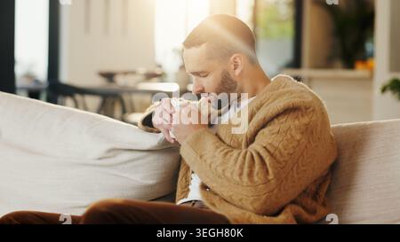 Sniffing, coffee and man on couch in home, chilling or comfortable on weekend with caffeine beverage. Fresh, scent and person with tea on peaceful Stock Photo