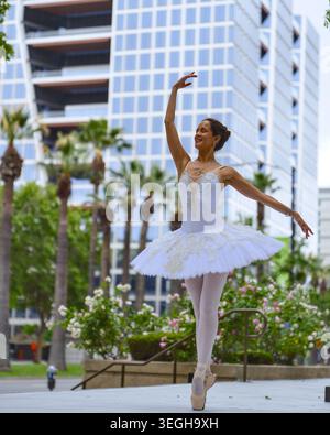 Ballerina dancing on pointe in urban plaza with modern city skyline Stock Photo