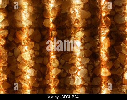 Abstract illuminated Himalayan salt wall texture featuring glowing warm light, natural crystal stones, and repeating vertical patterns. Decorative. Stock Photo