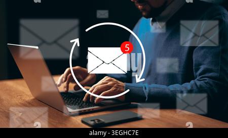Working on laptop and checking email notifications in a home office setting Stock Photo