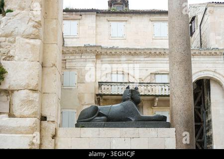 A majestic granite sphinx guards ancient stone structures and a towering column at Diocletian's Palace in Split, Croatia. Stock Photo