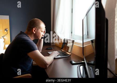 Man feeling stress and headache while telecommuting on laptop at a desk Stock Photo