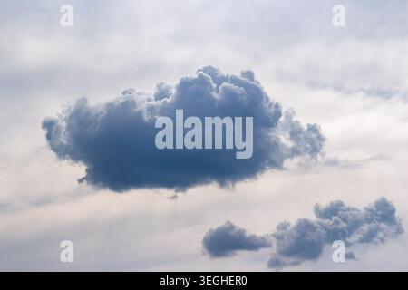Massive dark storm cloud drifting across the bright sky, a dramatic weather formation capturing the essence of heavy overcast atmosphere during a mood Stock Photo