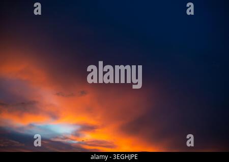 Gorgeous sunset fills the sky with hues of orange and purple, casting a warm glow over the peaceful horizon. Soft clouds of pastel shades. Bright epic Stock Photo