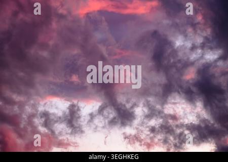Dramatic cloudy sky during twilight, featuring rich purples and glowing pink and reddish-orange light. Evaporation after storm. Colorful skyscape Stock Photo
