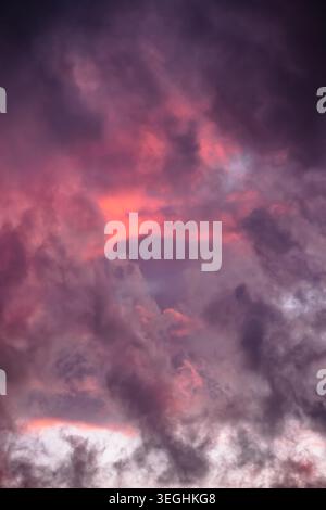 Dramatic cloudy sky during twilight, featuring rich purples and glowing pink and reddish-orange light. Evaporation after storm. Colorful skyscape Stock Photo