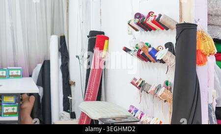 Sewing threads and colorful fabric rolls displayed on shelves in a tailor shop Stock Photo