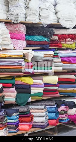 Shelves stacked with colorful fabric bolts and lace rolls in a textile shop Stock Photo