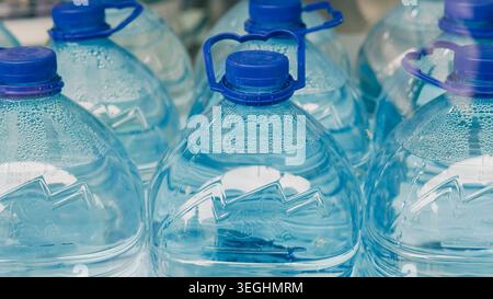 A group of plastic water bottles with blue caps stored together in a row Stock Photo