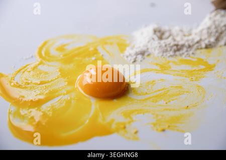 Raw egg yolk with flour and smeared egg mixture on white surface Stock Photo