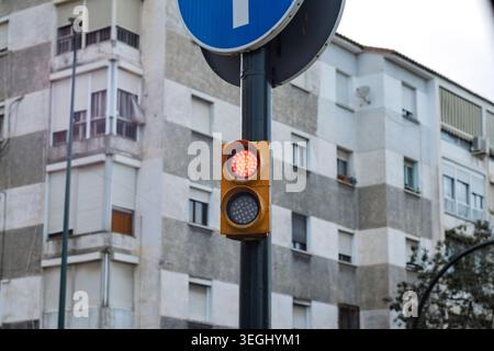 Red led traffic light active on an urban pole in front of residential buildings Stock Photo