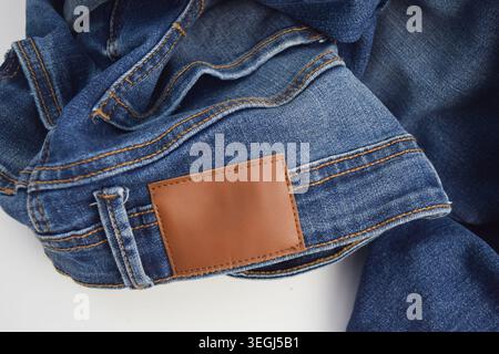 A blank brown leather label patch on the waistband of blue denim jeans, mockup copy space. Stock Photo