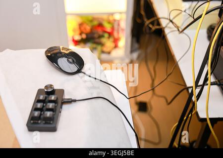 Computer mouse and external shortcut keypad resting on white workspace desk showing busy and frustrated atmosphere with messy cable wire clutter surro Stock Photo