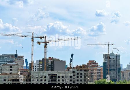 Urban Development: Tower Cranes Constructing Modern High-Rise Buildings Against Cloudy Skyline Stock Photo
