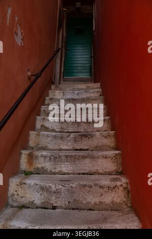 Worn concrete staircase with a green wooden door in a narrow alley in the Old Town of Rovinj, Croatia. Stock Photo