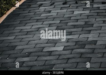 Top down view of grey interlocking dog bone shape concrete paving stones on a walkway. Stock Photo
