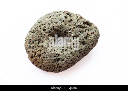 Ancient stone weight with central hole photographed isolated on white background, showing porous texture and rounded shape, object shaped by human wor Stock Photo