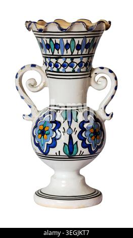 Decorative ceramic vase with two handles and scalloped rim showing hand‑painted floral and geometric patterns in blue, green and black on white glaze, Stock Photo