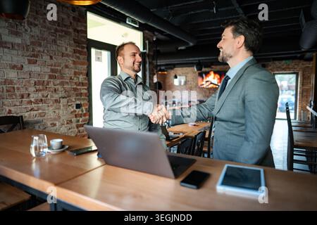 Businessmen shaking hands making partnership deal in cafe Stock Photo