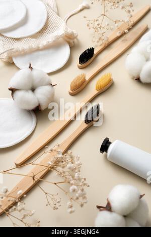Eco-friendly bathroom accessories with bamboo toothbrushes, reusable cotton pads and natural skincare products in minimal beige flat lay composition. Stock Photo