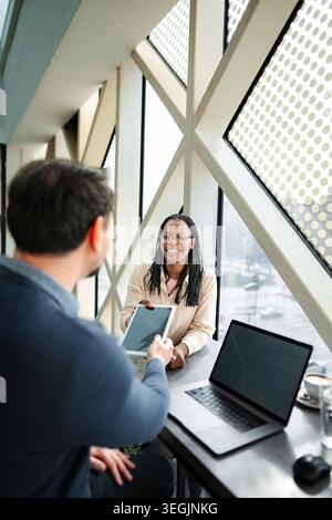 Coworkers exchanging data using digital tablet during business meeting Stock Photo