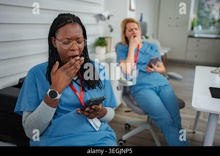 Tired medical workers yawning during long shift break Stock Photo