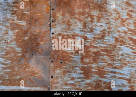 Close up photograph of weathered rusty sheet metal with visible screws and oxidized surface patterns Stock Photo