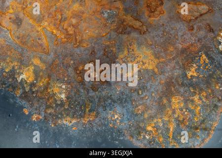 Close up image of rust corrosion on a weathered black metal surface with rich orange, brown and blue tones Stock Photo