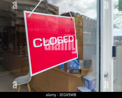 Red closed sign hanging on a glass door of a local shop Stock Photo