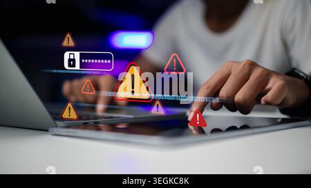Hand using laptop and tablet with warning triangle alert icons. Concept of cyber security breach, data hacking, computer virus threat, and password id Stock Photo