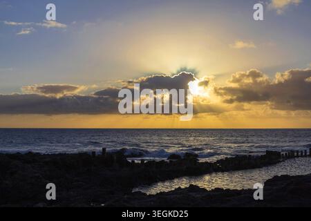 Golden sun rays shining through dramatic clouds above the Atlantic Ocean near Agaete, Gran Canaria, Canary Islands, Spain. Stock Photo