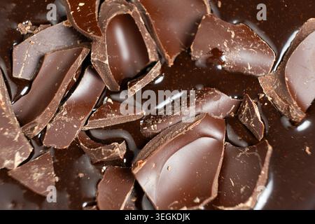 Dark chocolate chunks into liquid melted chocolate sauce background Stock Photo