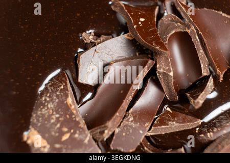Dark chocolate chunks into liquid melted chocolate sauce background Stock Photo