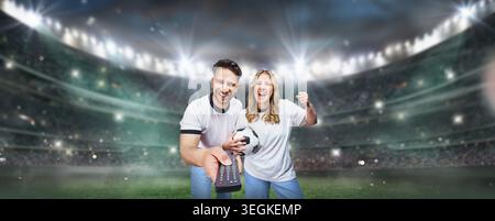soccer fans family switching on a soccer game using the remote control on the TV. textured soccer game field with neon fog - center, midfield. Stock Photo