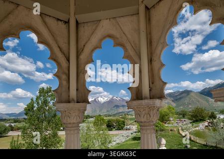 Ornate architectural arches frame a vibrant natural landscape with mountains, trees, and sky Stock Photo