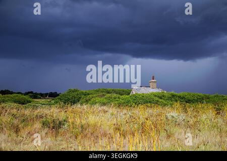 Aldeburgh, Suffolk, England, July 6th, 2025, landscape photograph of a derelict cottage roof against a background of dark storm clouds Stock Photo
