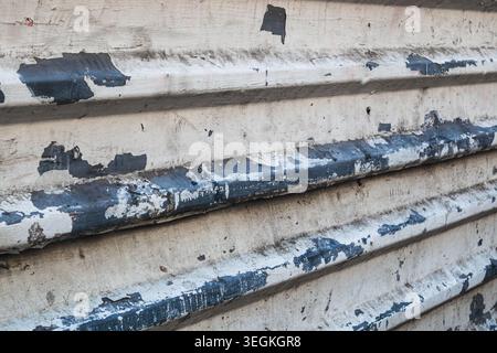 Close-up of peeling paint on corrugated metal siding. Industrial surface with visible rust and decay Stock Photo