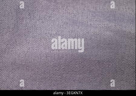 Close-up texture of a woven fabric with a subtle purple hue and visible threads Stock Photo