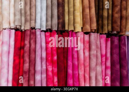 Fabric swatches arranged in rows displaying a gradient of colors from light pink to deep fuchsia and various shades of brown. Highlighting a textile c Stock Photo