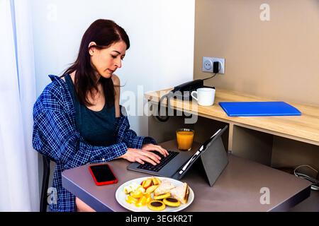 Woman remote working during breakfast, enjoying morning routines Stock Photo