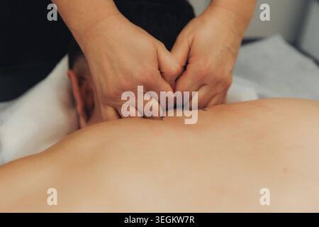 Two hands gently press into a person's spine Stock Photo
